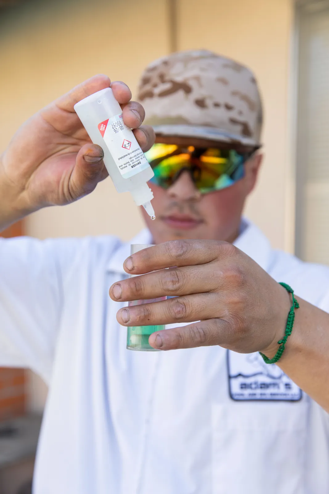 Person in white shirt and colorful cap holding a small white rectangular device or test strip.