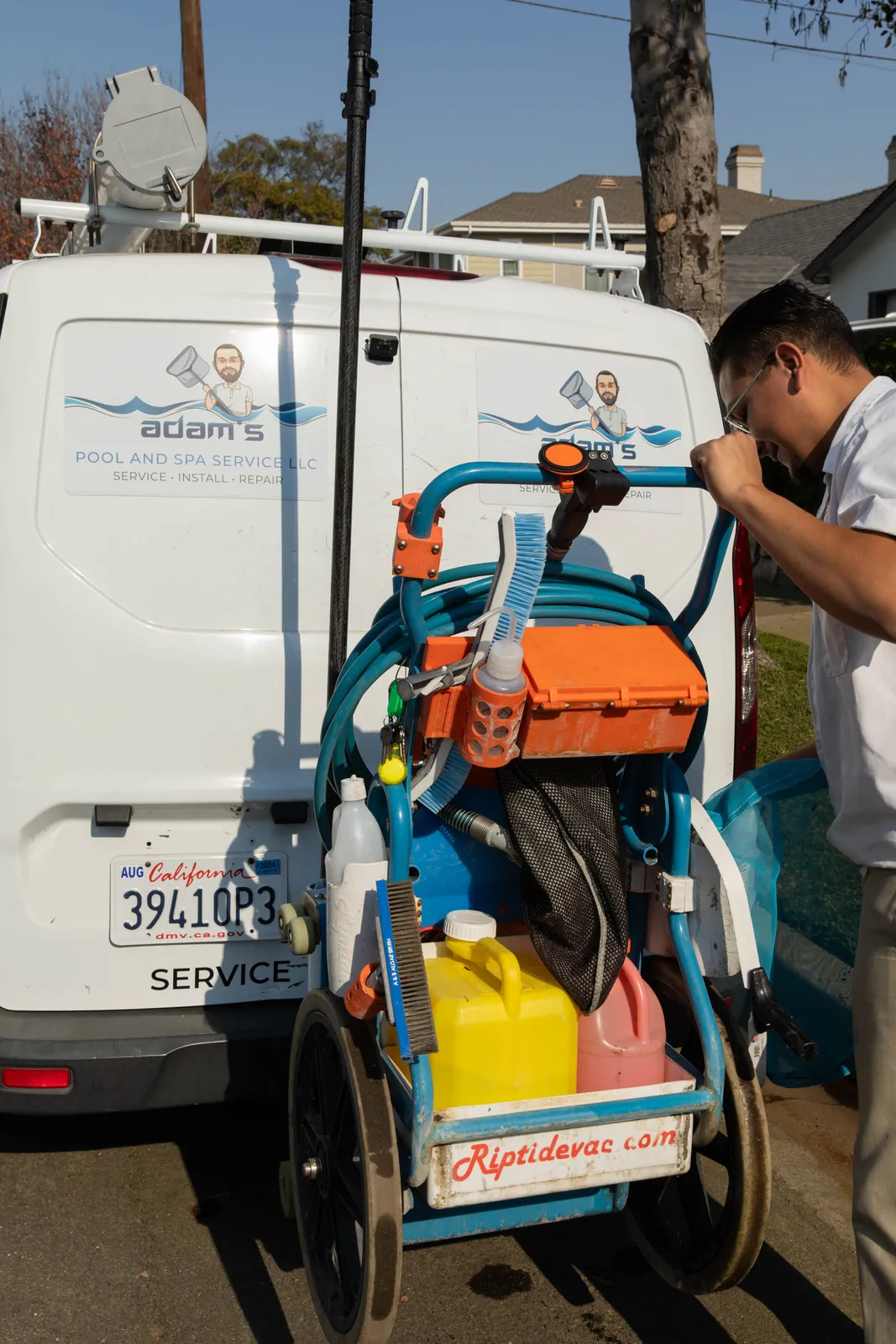 Service technician working on pool equipment attached to residential property, wearing work clothes.